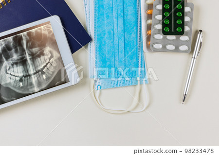 Doctor reviews panoramic image dental x-rays on digital tablet in order to prescribe treatment that is effective for patient based results examination. 98233478