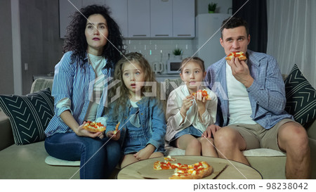 Parents and kids watch movie with zombified expression Parents and kids watch movie with zombified expression 98238042