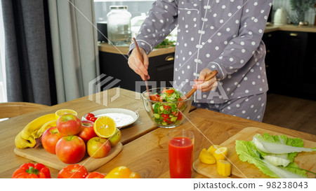 Housewife mixes vegetable salad and takes care about health Housewife mixes vegetable salad and takes care about health 98238043