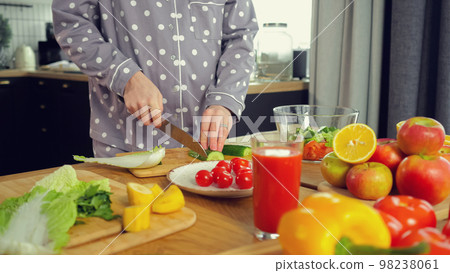 Pregnant housewife makes salad and chops vegetables on board 98238061
