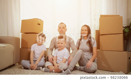 Family with excited expression sits on floor among boxes 98238066