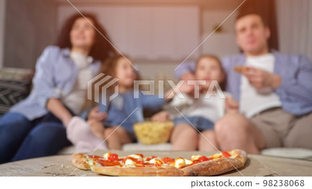 Mother takes pizza and enjoys watching movie with family Mother takes pizza and enjoys watching movie with family 98238068