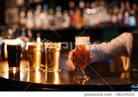 bartender hands a glass of tulip frothy draft beer to the bar 98239105