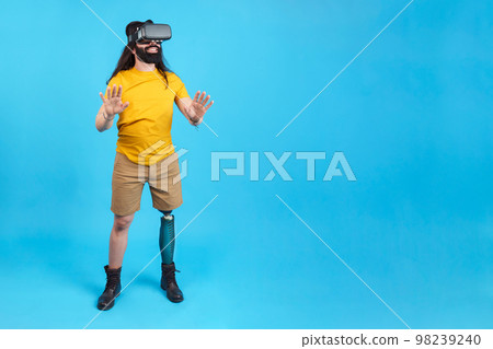 Man with prosthetic leg gesturing while using a virtual goggles Man with prosthetic leg gesturing while using a virtual goggles 98239240