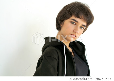 Young woman with black short hair posing in studio. Dressed in a black Young woman with black short hair posing in studio. Dressed in a black 98239387