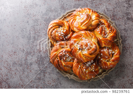 Swedish cinnamon rolls kanelbullar topped with pearl sugar close-up on a plate. Horizontal top view 98239761