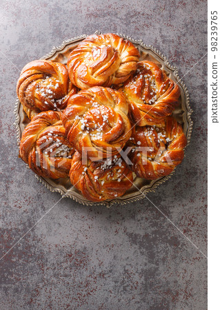 Cinnamon roll or kanelbulle is a famous Swedish pastry close-up on a plate. Vertical top view 98239765