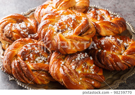 Swedish cinnamon rolls kanelbullar topped with pearl sugar close-up on a plate. Horizontal 98239770