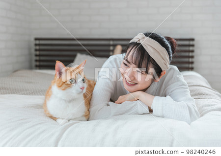 Asian woman playing with pet cat in bedroom at home Asian woman playing with pet cat in bedroom at home 98240246