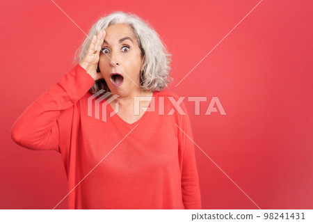 Mature woman looking at camera with a surprised look Mature woman looking at camera with a surprised look 98241431