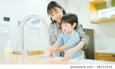 A mother helping a 2-year-old boy to wash his hands A mother helping a 2-year-old boy to wash his hands 98242039