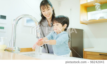 A mother helping a 2-year-old boy to wash his hands A mother helping a 2-year-old boy to wash his hands 98242041