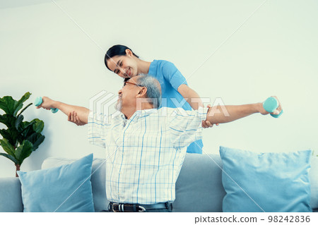 Contented senior patient doing physical therapy with the help of his caregiver. 98242836