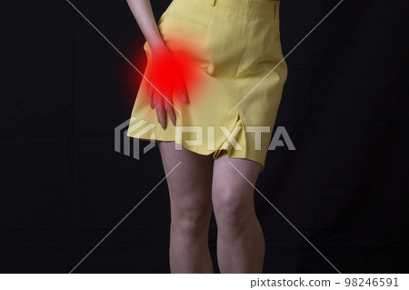 young woman experiencing pain in the hip joint on black background. 98246591