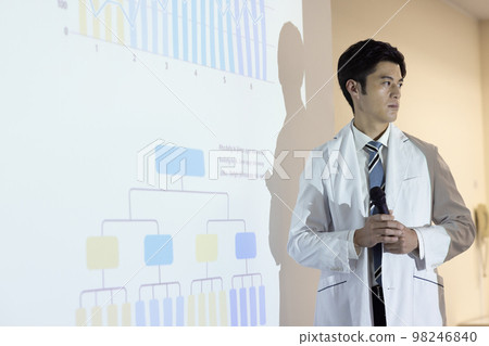 A man in a white coat giving a presentation 98246840