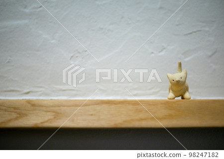 An unglazed pottery cat figurine in front of a diatomite wall 98247182