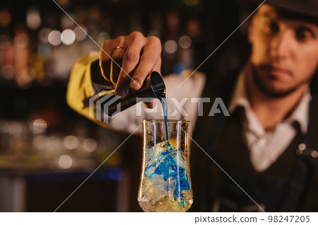 bartender mixes a Blue Lagoon cocktail in a glass at bar counter bartender mixes a Blue Lagoon cocktail in a glass at bar counter 98247205