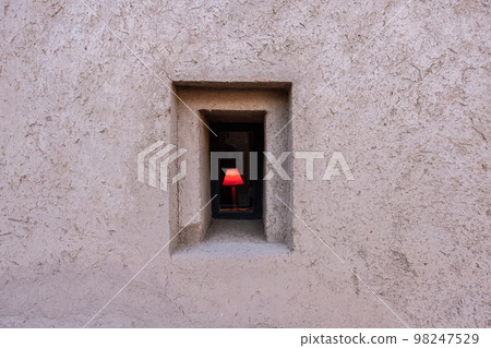 Red lamp light on a window of a kasbah with mud walls 98247529