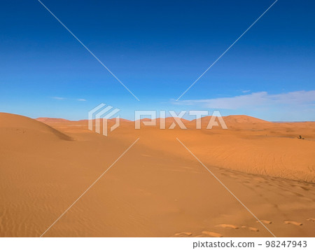 The sahara desert and its sand dunes with a blue sky as a background. 98247943