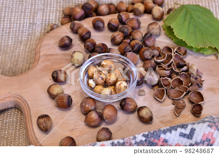 Peeled and unpeeled hazelnuts lie on a cutting board. Peeled and unpeeled hazelnuts lie on a cutting board. 98248687