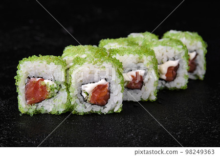 sushi roll with Tuna inside and green flying fish roe on top on black background sushi roll with Tuna inside and green flying fish roe on top on black background 98249363