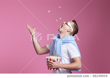 handsome man in 3d glasses throwing up and eating popcorn 98249959