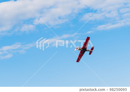 Light aircraft flying in blue sky and doing stunts 98250093