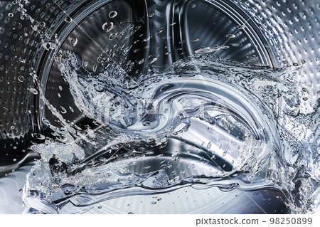 Washing machine drum with clean water flow and splashes. Laundry, washing powder concept. 98250899
