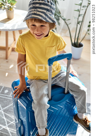 A child sitting on a suitcase have fun and laughs, waiting for a trip on vacation 98251023