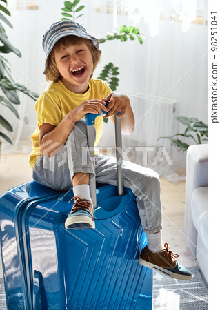 A child sitting on a suitcase have fun and laughs, waiting for a trip on vacation 98251041