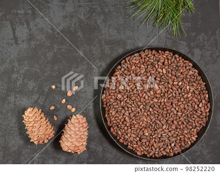 Pine cones and nuts in a frying pan on a dark background with space for copying Pine cones and nuts in a frying pan on a dark background with space for copying 98252220