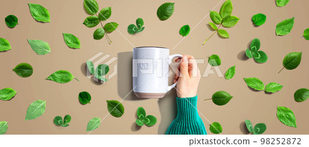 Person holding a mug with green leaves 98252872