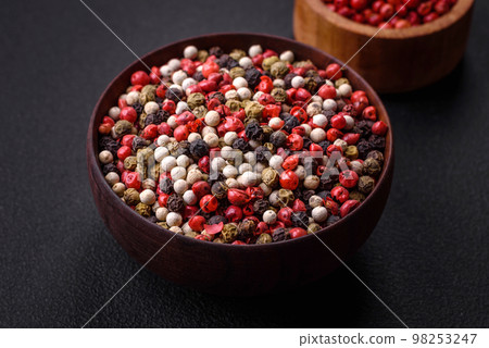 Allspice peas in a wooden bowl on a black concrete background Allspice peas in a wooden bowl on a black concrete background 98253247