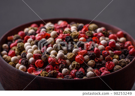 Allspice peas in a wooden bowl on a black concrete background 98253249