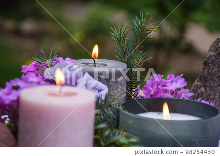 Closeup burning candles purple flowers stone on blurred background 98254430