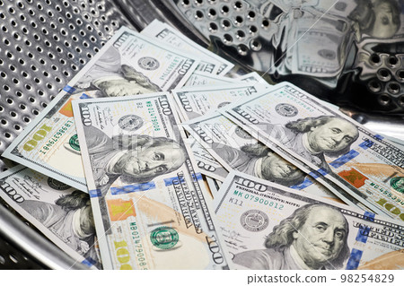 Close-up of washing dollars in machine, money laundering, financial fraud concept Close-up of washing dollars in machine, money laundering, financial fraud concept 98254829