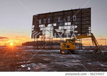 Abandoned outdoor drive in movie theater at sunset with excavator ready for demolition Abandoned outdoor drive in movie theater at sunset with excavator ready for demolition 98254937