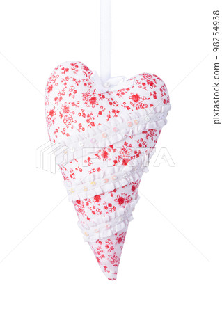 White fabric heart with red flowers on a satin ribbon isolated on white. Textile heart decorated with white lace ribbons and glitters. Red elongated heart handmade pillow. Valentine's day decorations. White fabric heart with red flowers on a satin ribbon isolated on white. Textile heart decorated with white lace ribbons and glitters. Red elongated heart handmade pillow. Valentine's day decorations. 98254938