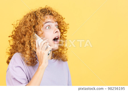 Surprised woman with curly hair talking to the mobile Surprised woman with curly hair talking to the mobile 98256195