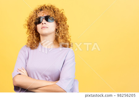 Rude woman with sunglasses standing with arms crossed 98256205