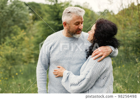 Close up romantic couple standing in autumn park and hugging in daytime. Man and woman wearing blue sweaters. Woman is brunette and man is gray. Close up romantic couple standing in autumn park and hugging in daytime. Man and woman wearing blue sweaters. Woman is brunette and man is gray. 98256498