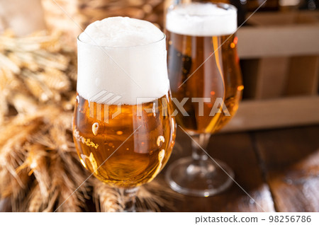 Glass of light craft beer on a wooden table. Beer is poured into a glass with foam and bubbles.  98256786