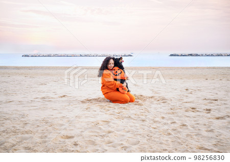 Halloween dog dressed as a pumpkin on the beach. Black Cocker Spaniel in festive clothes plays. 98256830