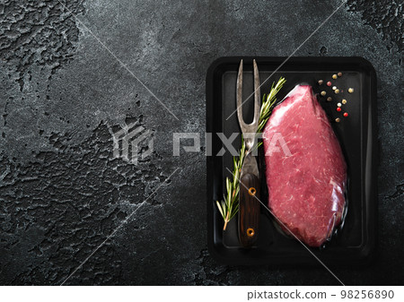 Vacuum tray with fresh raw beef steak sirloin fillet with pepper,rosemary and barbeque fork 98256890