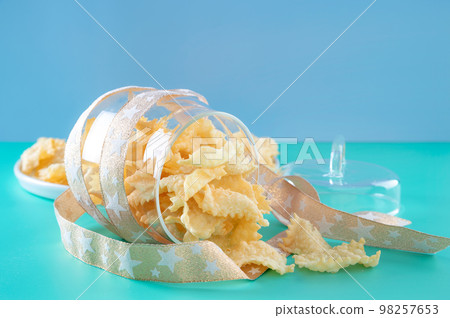 Sfrappole or chiachiere or angel wings on a bright blue background. Italian Carnival and TYPICAL Sfrappole or chiachiere or angel wings on a bright blue background. Italian Carnival and TYPICAL 98257653