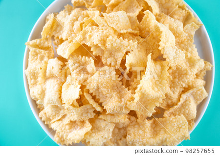 Sfrappole or chiachiere or angel wings on a bright blue background. Italian Carnival and TYPICAL Sfrappole or chiachiere or angel wings on a bright blue background. Italian Carnival and TYPICAL 98257655