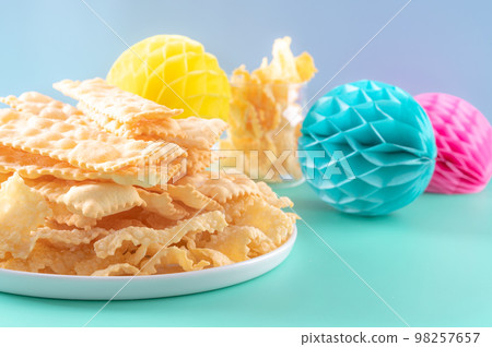 Sfrappole or chiachiere or angel wings on a bright blue background. Italian Carnival and TYPICAL Sfrappole or chiachiere or angel wings on a bright blue background. Italian Carnival and TYPICAL 98257657