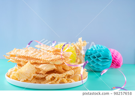 Sfrappole or chiachiere or angel wings on a bright blue background. Italian Carnival and TYPICAL Sfrappole or chiachiere or angel wings on a bright blue background. Italian Carnival and TYPICAL 98257658