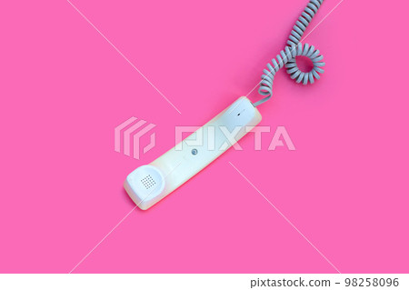 Handset of landline phone on pink background. 98258096