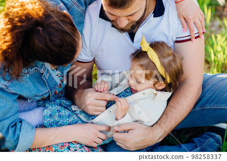 top view. a little daughter in the arms of mom and dad on a lawn. family picnic 98258337